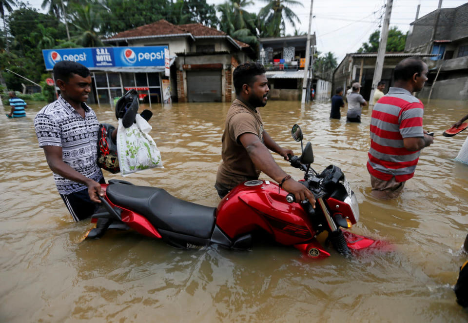 A man pushes his bike through a flooded road in Biyagama, Sri Lanka, May 17, 2016. (Reuters/Dinuka Liyanawatte)