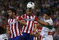 Atletico Madrid's David Villa (C) heads the ball next his teammate Raul Garcia and Elche's Cristian Sapunaru during their Spanish first division soccer match at Vicente Calderon stadium in Madrid April 18, 2014. REUTERS/Juan Medina