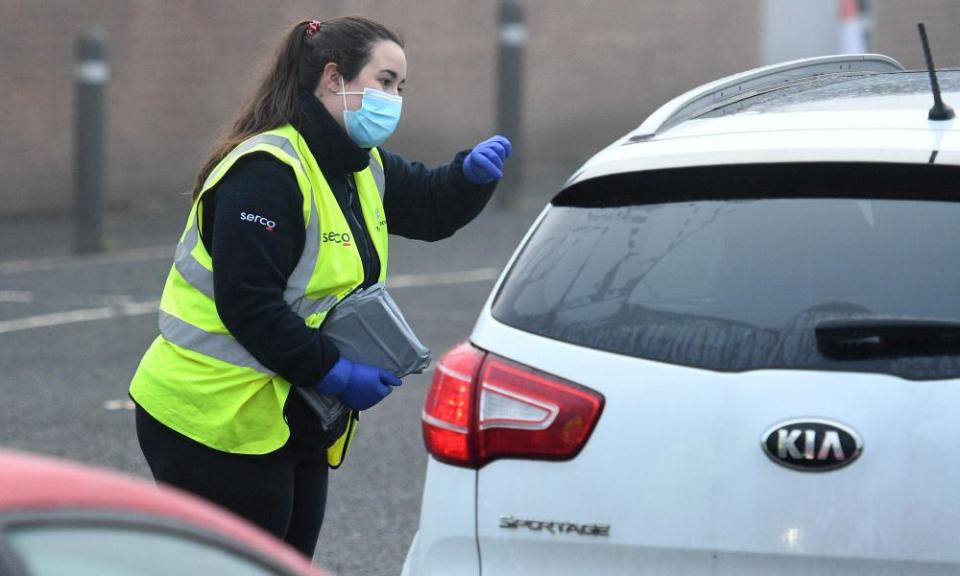 A Serco worker passes coronavirus test kits to members of the public arriving at a temporary facility in Walsall.