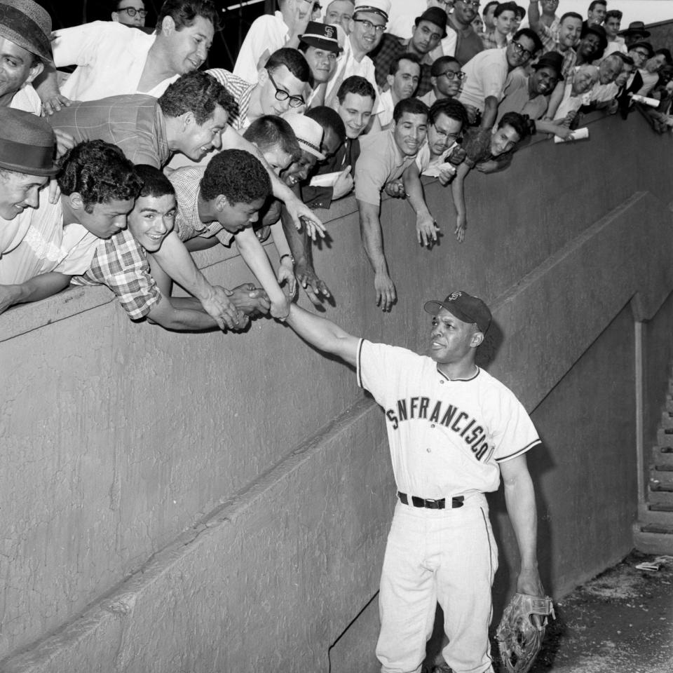 Bleacher fans lean over the wall to greet Mays as he and the San Francisco Giants made their first appearance against <a class="link " href="https://sports.yahoo.com/mlb/teams/ny-mets/" data-i13n="sec:content-canvas;subsec:anchor_text;elm:context_link" data-ylk="slk:the Mets;sec:content-canvas;subsec:anchor_text;elm:context_link;itc:0">the Mets</a> ca. 1962. <br><span class="copyright">Bettmann Archive/Getty Images</span>