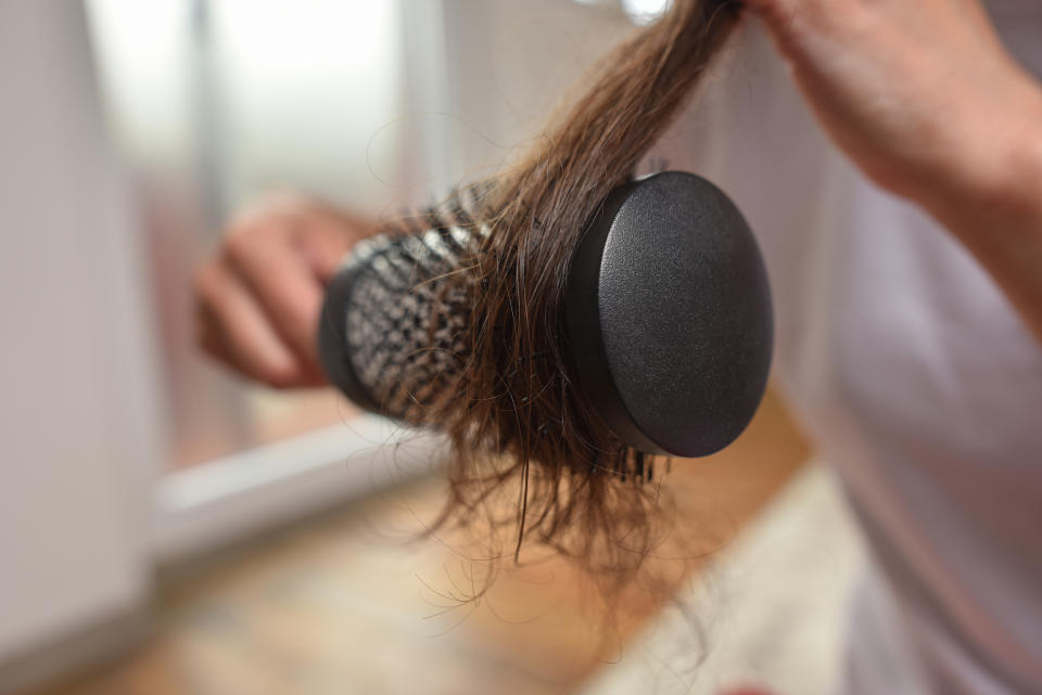 Person holding a hairbrush entangled with strands of hair