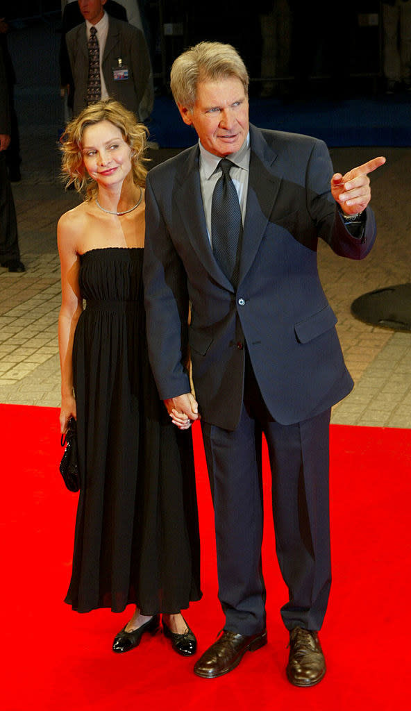 Harrison is pointing at something on the red carpet with calista