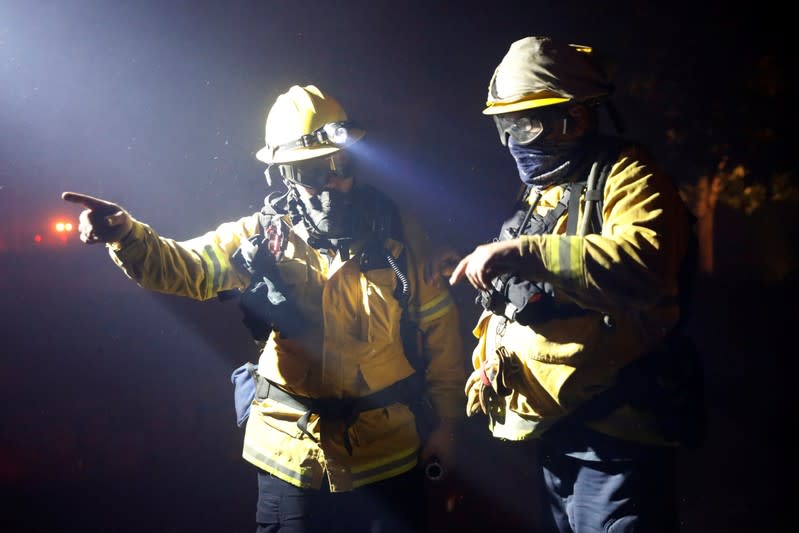 Two firefighters discuss a plan while battling the Kincade fire in Geyserville, California