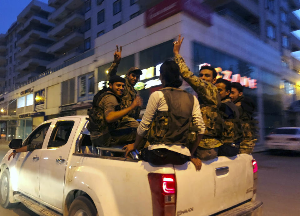 Turkish-backed Syrian opposition fighters from the Syrian National Army, flash the V-sign as they are driven through the town of Akcakale, Sanliurfa province, southeastern Turkey, on their way to enter over the border to Tel Abyad, Syria, Friday, Oct. 11, 2019. Turkey's vice president says Turkish troops and their allied Syrian opposition forces have advanced up to 8 kilometers (5 miles) deep into Syrian territory. (AP Photo/Emrah Gurel)