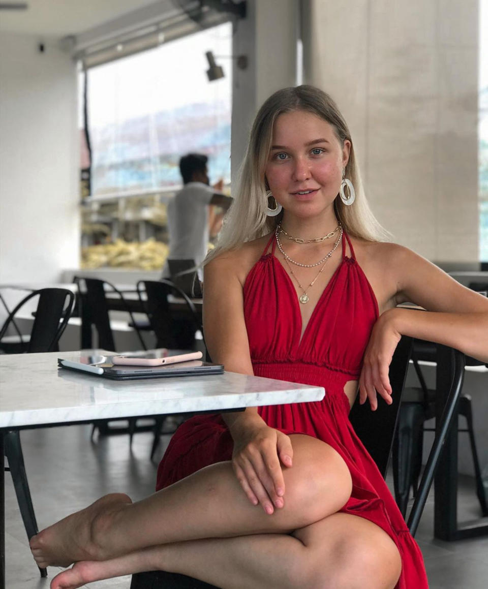 Anastasia Tropitsel is sitting in a cafe wearing a red dress. 