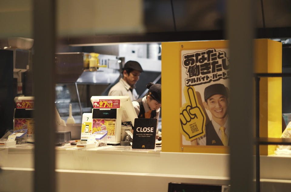 Staff members at a McDonald's store work behind a "Close" cashier sign as the shop shutters earlier than usual citing a system failure, in Tokyo, Friday, March 15, 2024. (AP Photo/Hiro Komae)