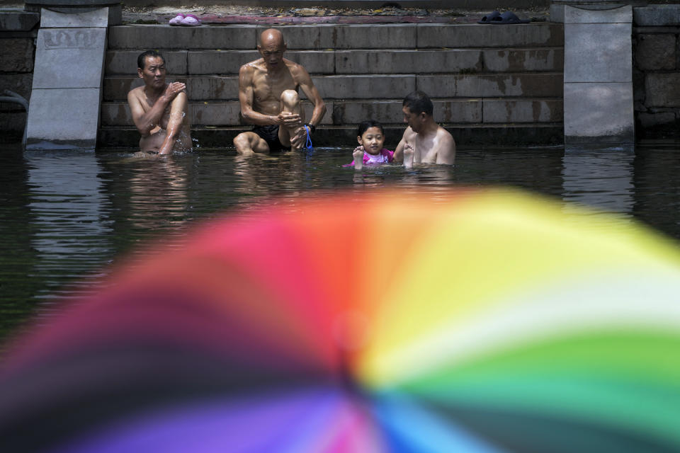 Residents cool off from a hot day at an urban waterway in Beijing, Monday, July 3, 2023. Heavy flooding has displaced thousands of people around China as the capital had a brief respite from sweltering heat. Beijing reported 9.8 straight days when the temperature exceeded 35 C (95 F), the National Climate Center said Monday. (AP Photo/Andy Wong)
