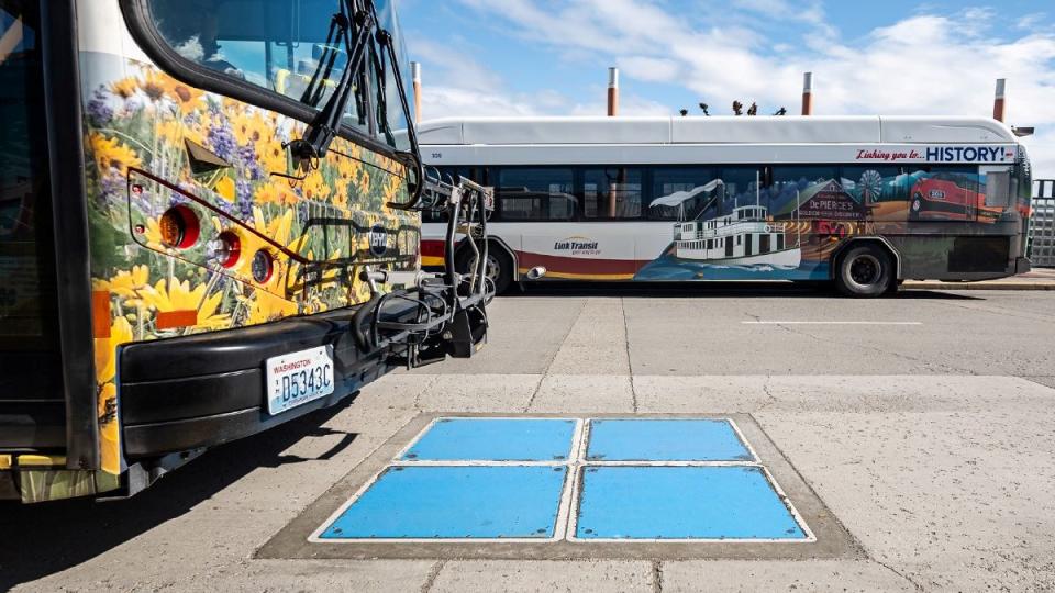 a couple of buses parked next to each other near inductive charging plates