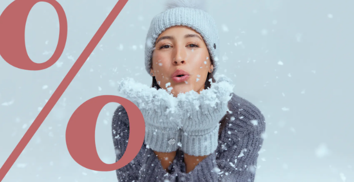 Frau pustet Schnee in die Kamera, daneben ein großes Prozent-Zeichen