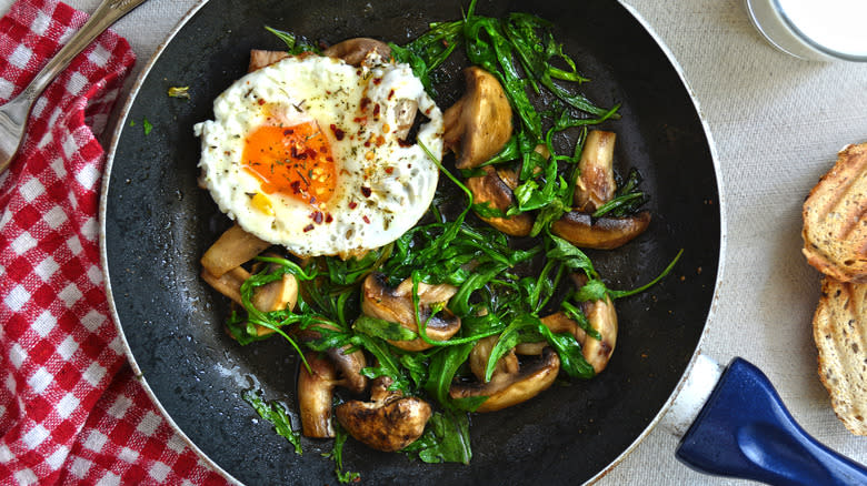 arugula in pan with mushrooms and egg