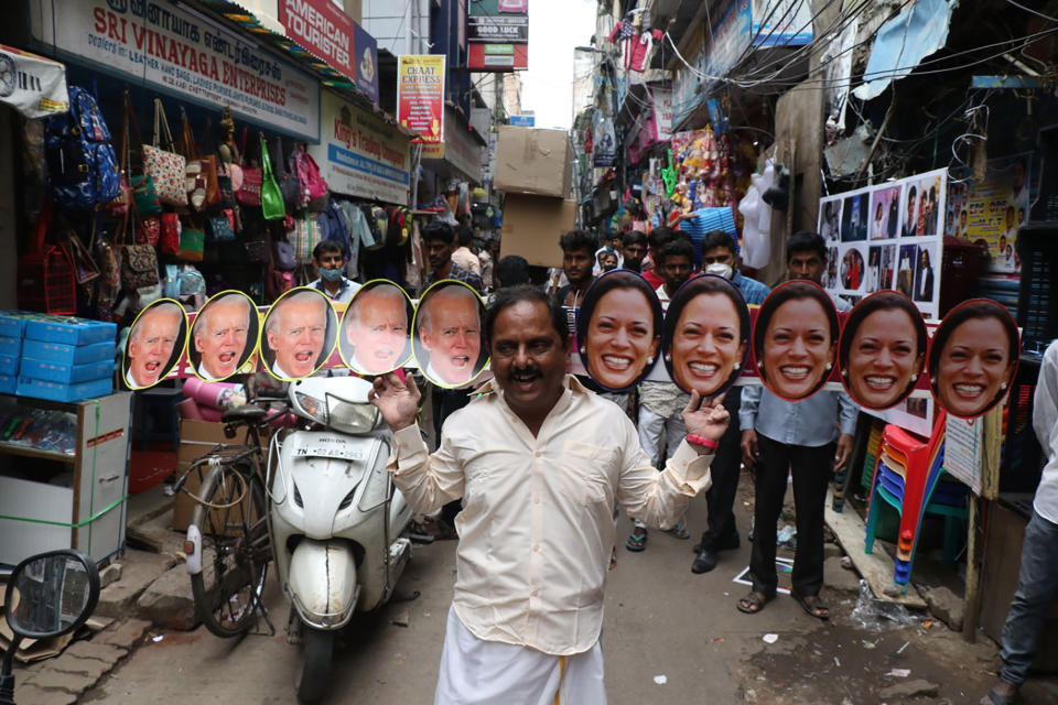 A man wears cut-outs of U.S.President-elect Joe Biden and Vice President-elect Kamala Harris and walks on a street in Chennai, India, Wednesday, Jan. 20, 2021. The inauguration of Biden and Harris is scheduled be held Wednesday. (AP Photo/R. Parthibhan)