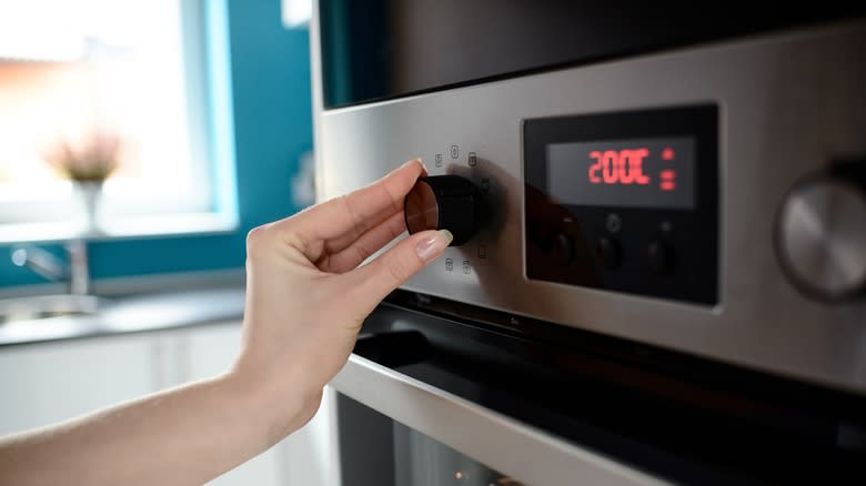 Hands setting oven temperature