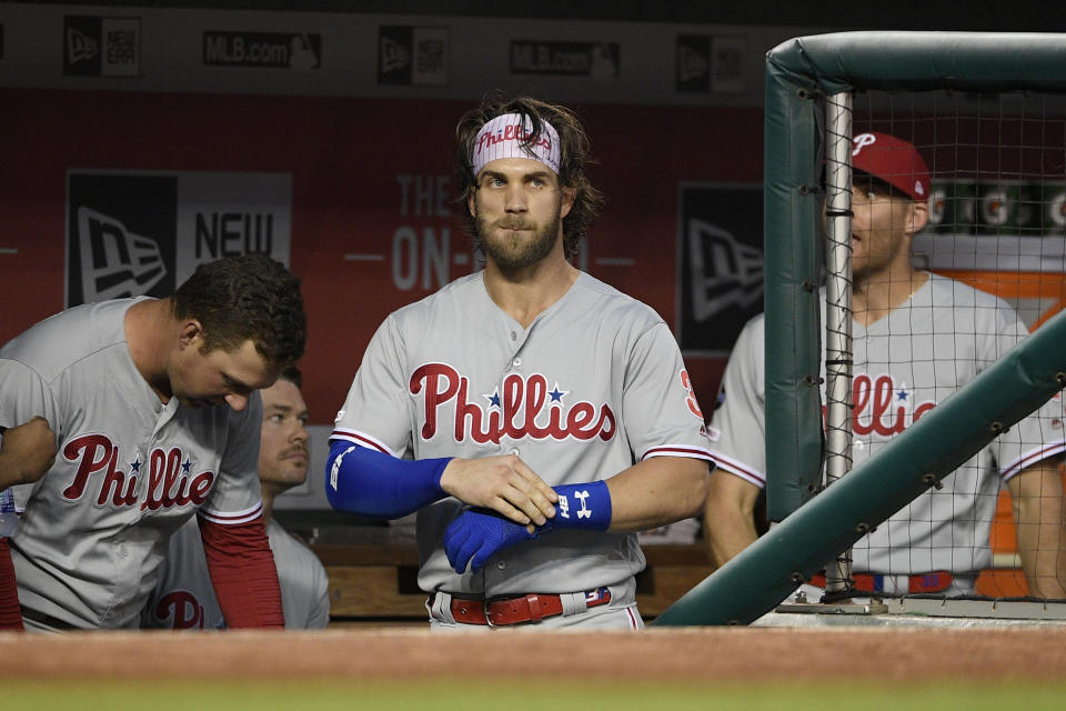 Philadelphia Phillies' Bryce Harper, center, stands in the dugout before a baseball game against the Washington Nationals, Monday, Sept. 23, 2019, in Washington. (AP Photo/Nick Wass)