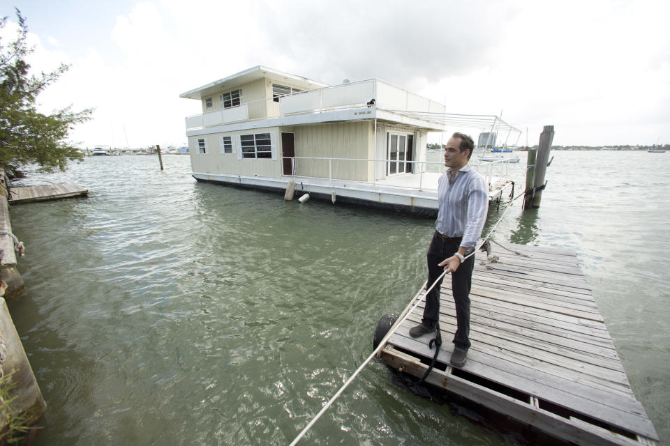 In this April 22, 2014 photo, Fane Lozman pulls his dock away from his home floating in the waters near North Bay Village, Fla., as he returns to the shoreline. Lozman caught legal lightning in a bottle last year when the U.S. Supreme Court agreed with him that his floating home was a house, not a vessel covered by maritime law. But the justices haven’t had the last word: Lozman is still fighting for compensation for the home, which was destroyed years ago. The Fort Lauderdale-based federal judge whose decision on the floating home was overturned, U.S. District Judge William Dimitrouleas, refused earlier this year to give Lozman any of the $25,000 bond posted by the city of Riviera Beach to pay for Lozman’s home in case he won. (AP Photo/J Pat Carter)