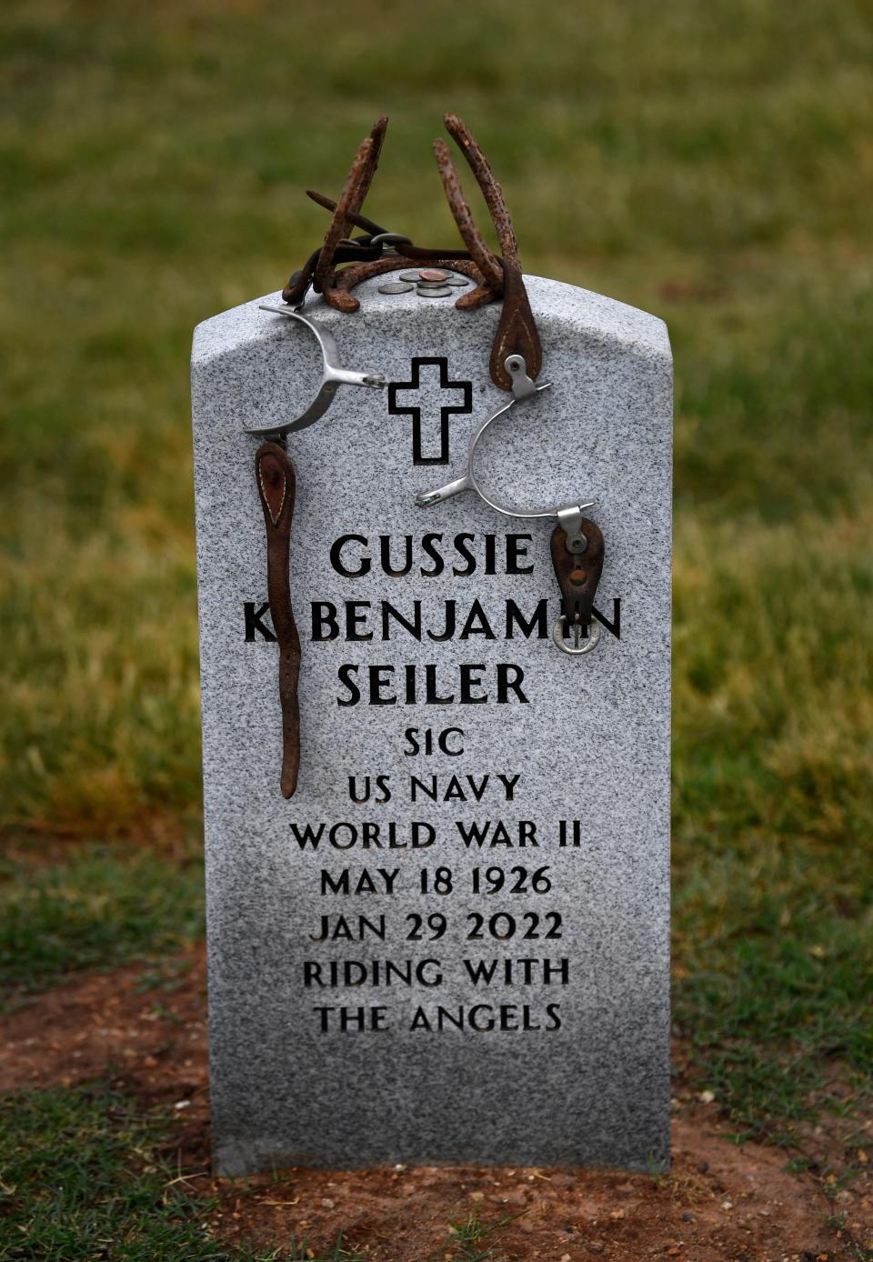 Spurs, horseshoes and coins rest atop the marker for Gussie K. Benjamin Seiler at Texas State Veterans Cemetery at Abilene Tuesday.