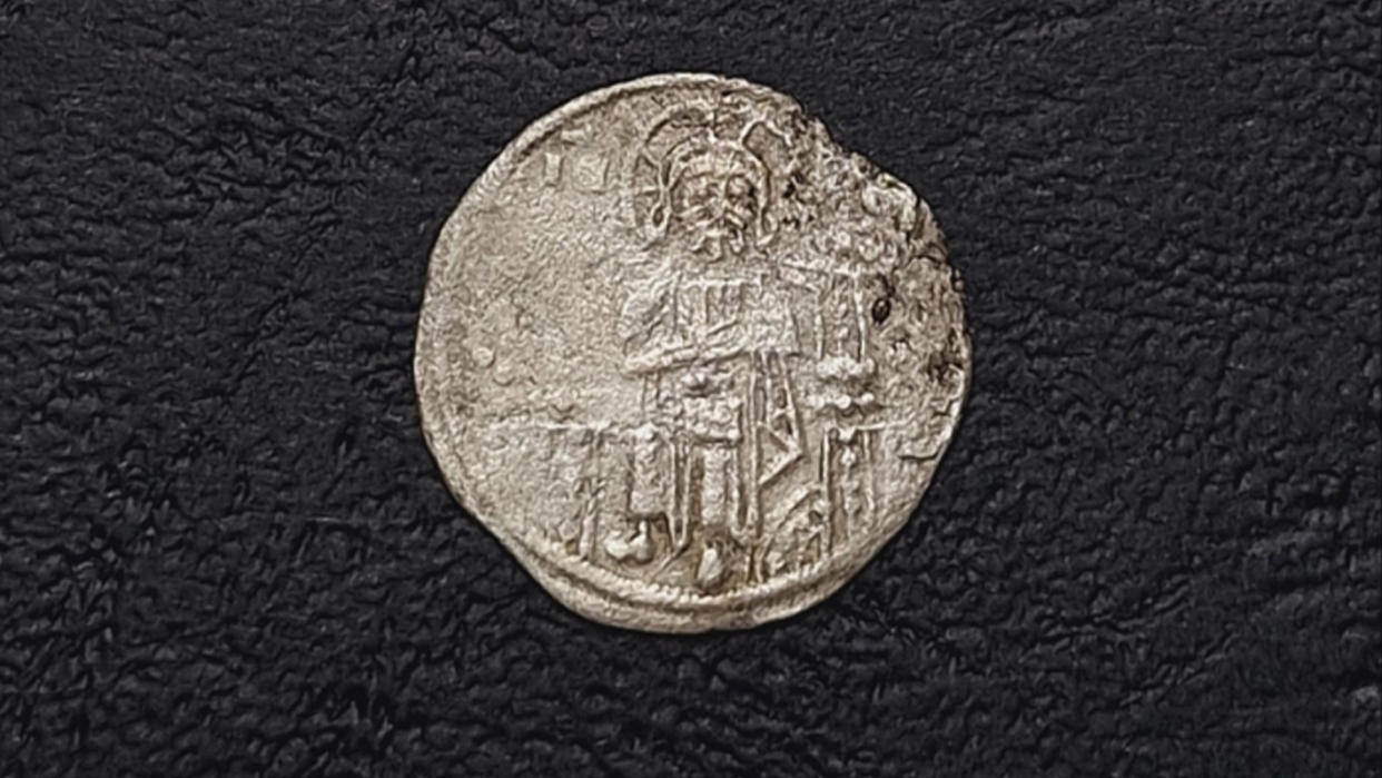  An ancient silver coin with stamp that depicts a seated Jesus. 