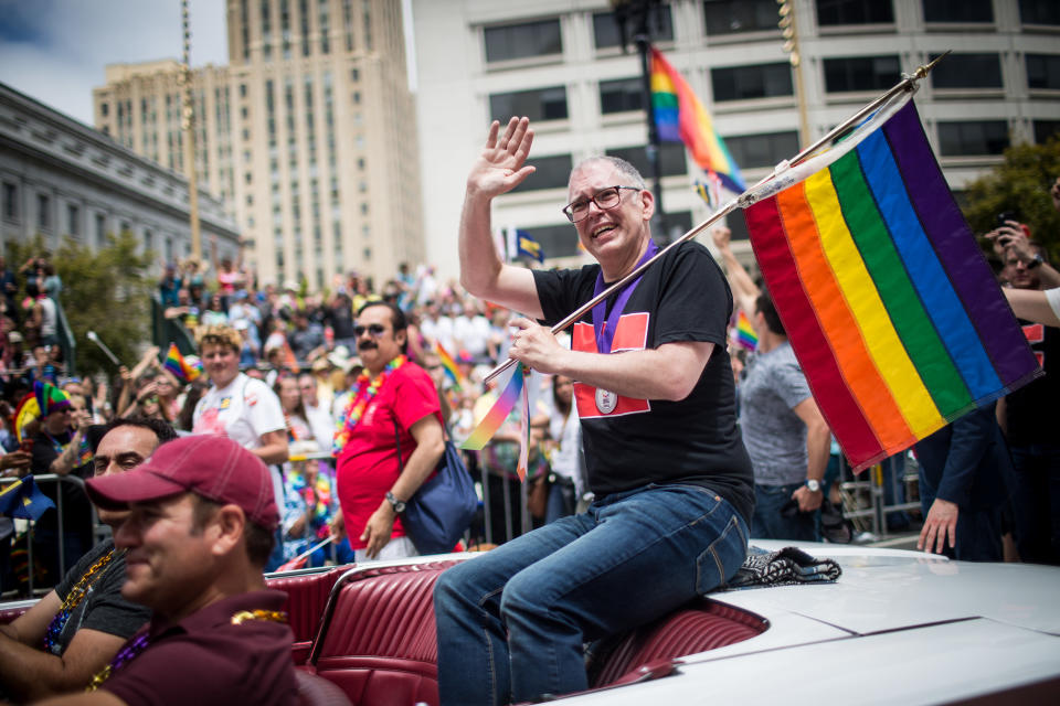 Supreme Court plaintiff Jim Obergefell, holding a rainbow flag, rides in a convertible in the San Francisco Gay Pride Parade.