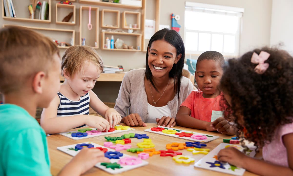 A teacher sitting at a table with her kindergarten students