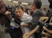 FILE - In this May 11, 2019, file photo, pro-democracy lawmaker Wu Chi-wai, center, scuffles with security guards at Legislative Council in Hong Kong. After nearly three decades in politics, the 58-year-old Wu, chairman of Hong Kong’s largest pro-democracy party, is stepping down Monday, Nov. 30, 2020. All 15 lawmakers in the pro-democracy camp have decided to resign to protest a Beijing resolution in early November that led to the disqualifications of four of their colleagues. (AP Photo/Vincent Yu, File)