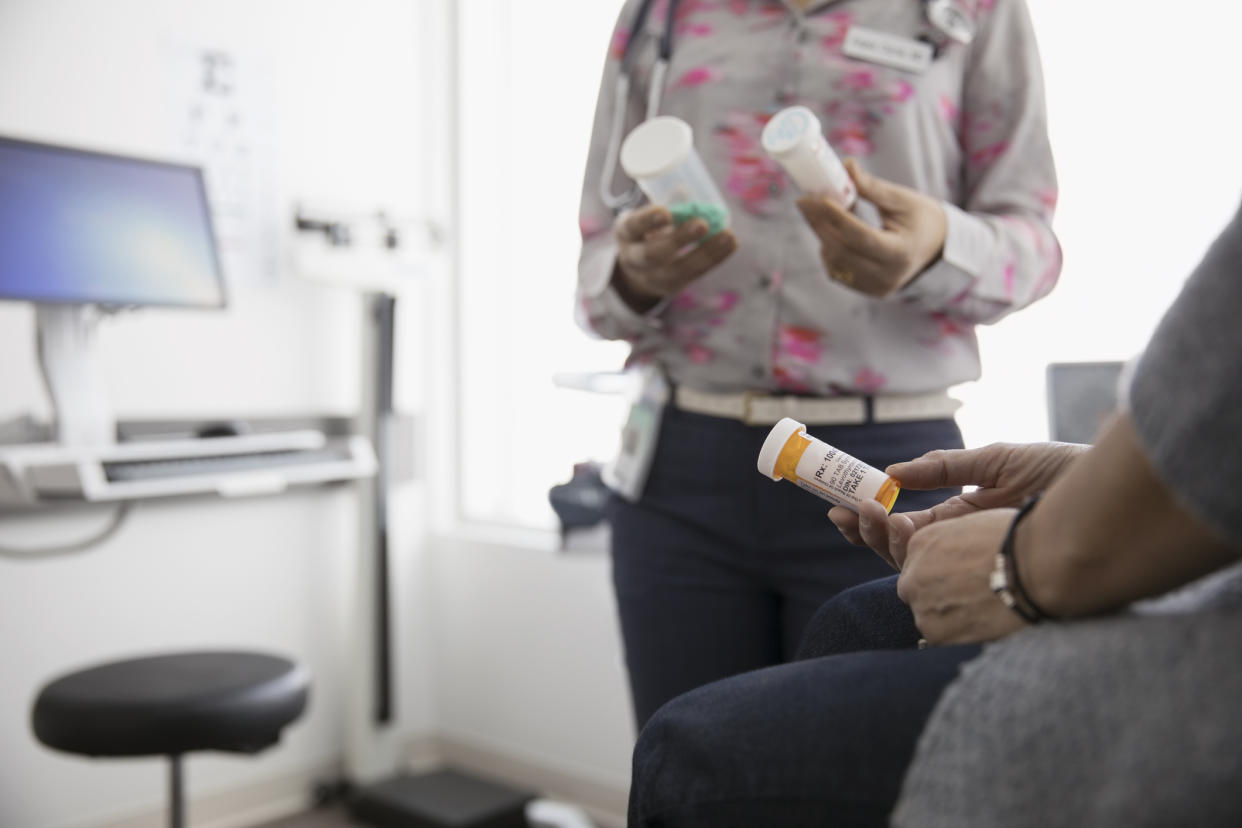 A doctor prescribes medication to a patient in a clinic exam room. (Getty Images)