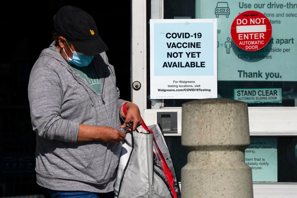 A customer walks past a sign indicating that a COVID-19 vaccine is not yet available at Walgreens, Wednesday, Dec. 2, 2020, in Long Beach, Calif.
