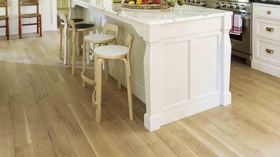 a white kitchen with a large island with a pot rack hanging over it