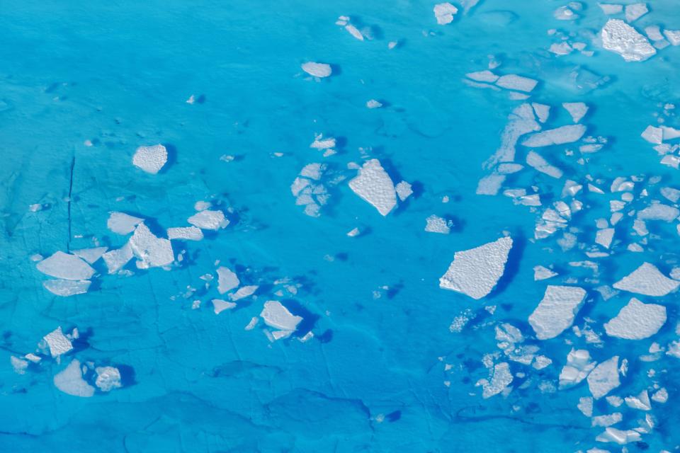 Chunks of ice float on pale blue water.