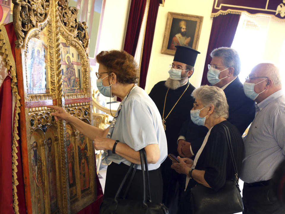 A cleric and others examine a pair of ornate, gilded doors that guard the altar of a church, at the Archbishopric in the capital Nicosia, Thursday, Sept. 16, 2021. The 18th century doors that were looted from the church of Saint Anastasios in the breakaway north of the ethnically divided island nation were repatriated from a Japanese art college after a long legal battle. (AP Photo/Philippos Christou)