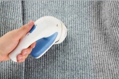 a hand using the fabric shaver on a ribbed sweater