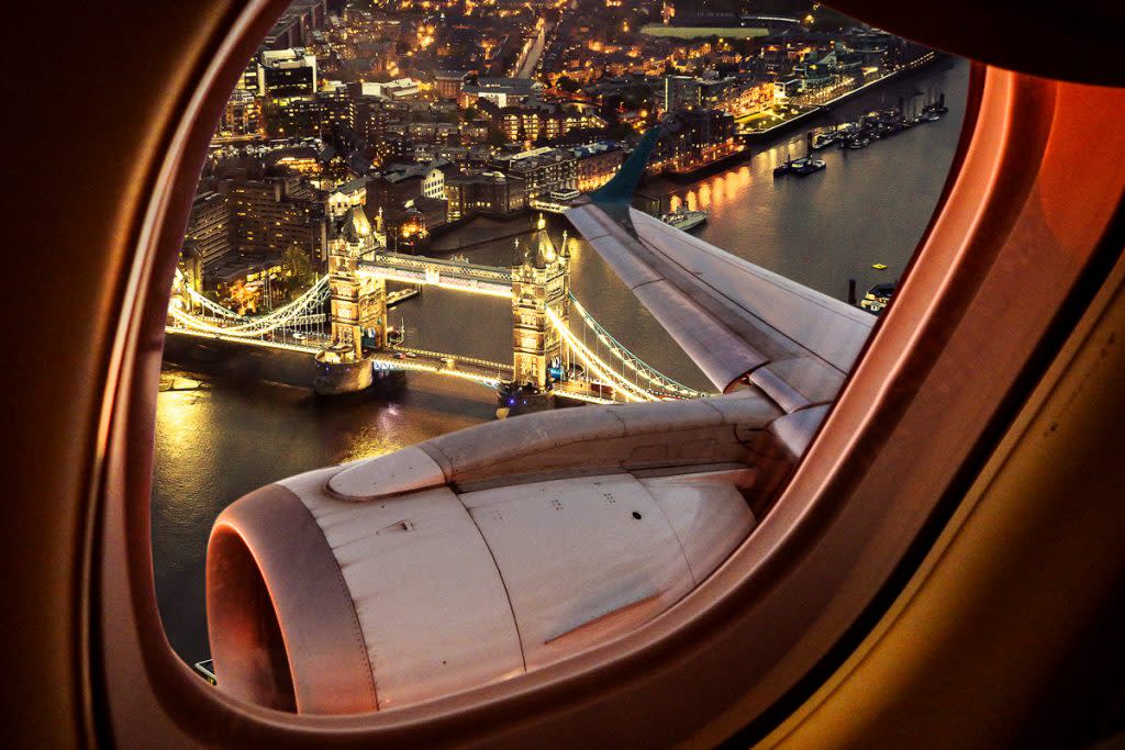 A city with bright lights is shown from the window of a plane. 