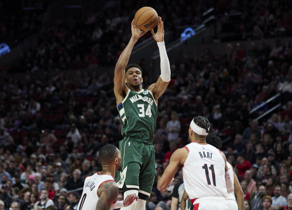 Milwaukee Bucks forward Giannis Antetokounmpo (34) passes the ball away from Portland Trail Blazers guard Damian Lillard (0) and guard Josh Hart during the second half of an NBA basketball game in Portland, Ore., Monday, Feb. 6, 2023. (AP Photo/Craig Mitchelldyer)