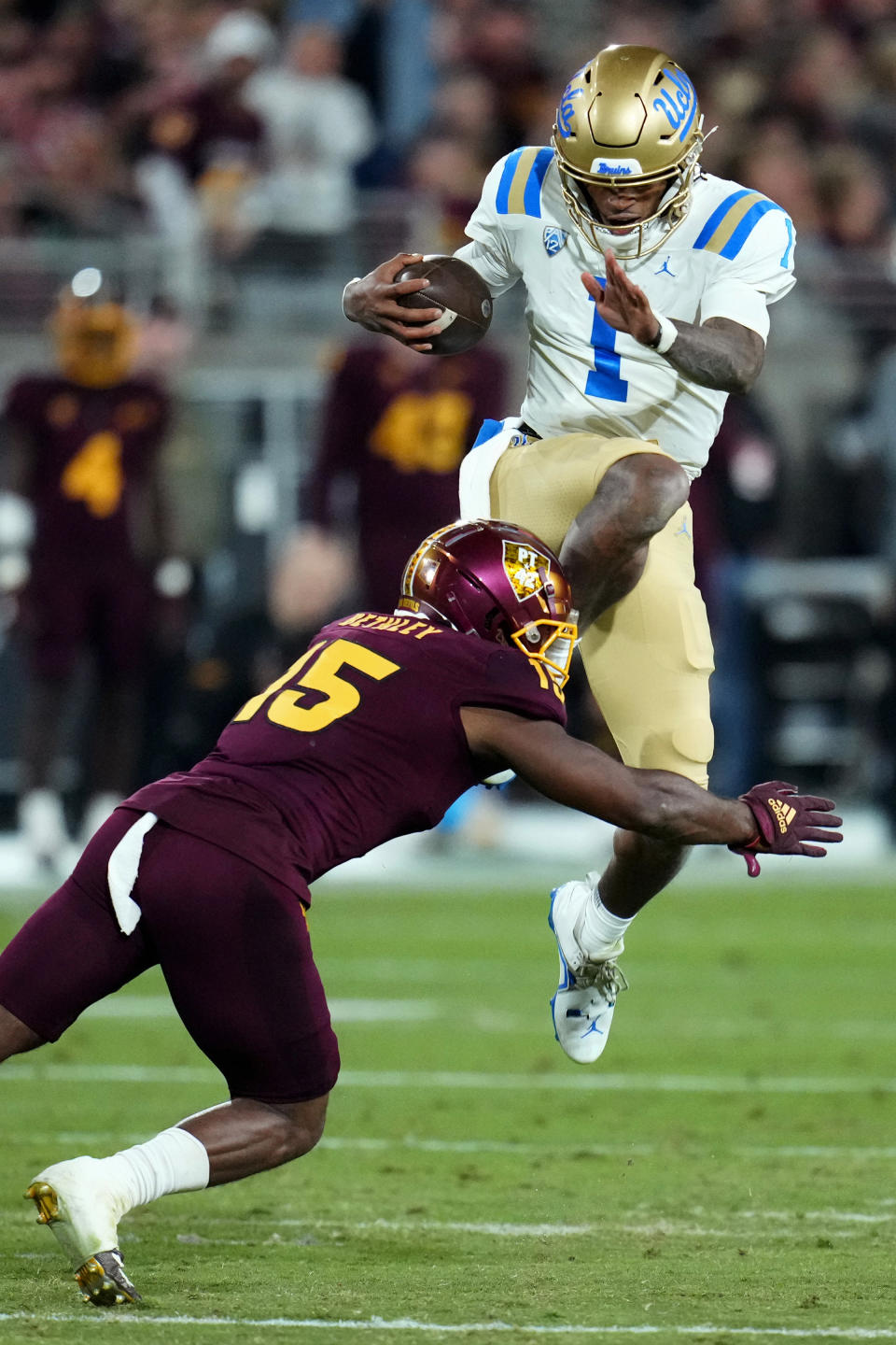 UCLA quarterback Dorian Thompson-Robinson (1) leaps over Arizona State defensive back Khoury Bethley (15) during the first half of an NCAA college football game in Tempe, Ariz., Saturday, Nov. 5, 2022. (AP Photo/Ross D. Franklin)