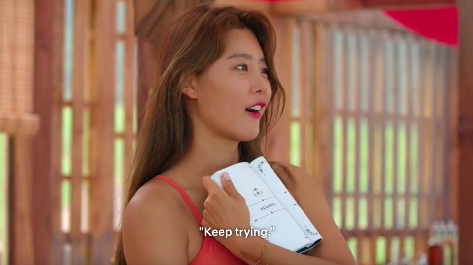 So-yeon opens the book to a page that reads "Keep trying," and gasps