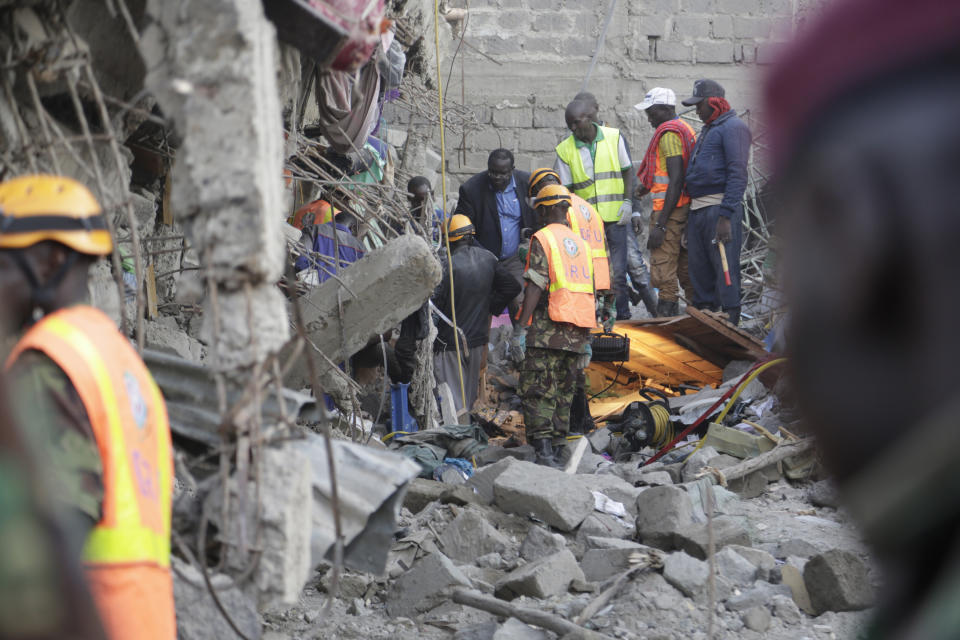 People and rescue workers attend the scene of a building that collapsed in Tasia Embakasi, an east neighbourhood of Nairobi, Kenya on Friday Dec. 6, 2019. A six-story building collapsed in Kenya's capital on Friday, officials said, with people feared to be trapped in the debris. Police say people have been rescued by residents using their bare hands. (AP Photo/Khalil Senosi)