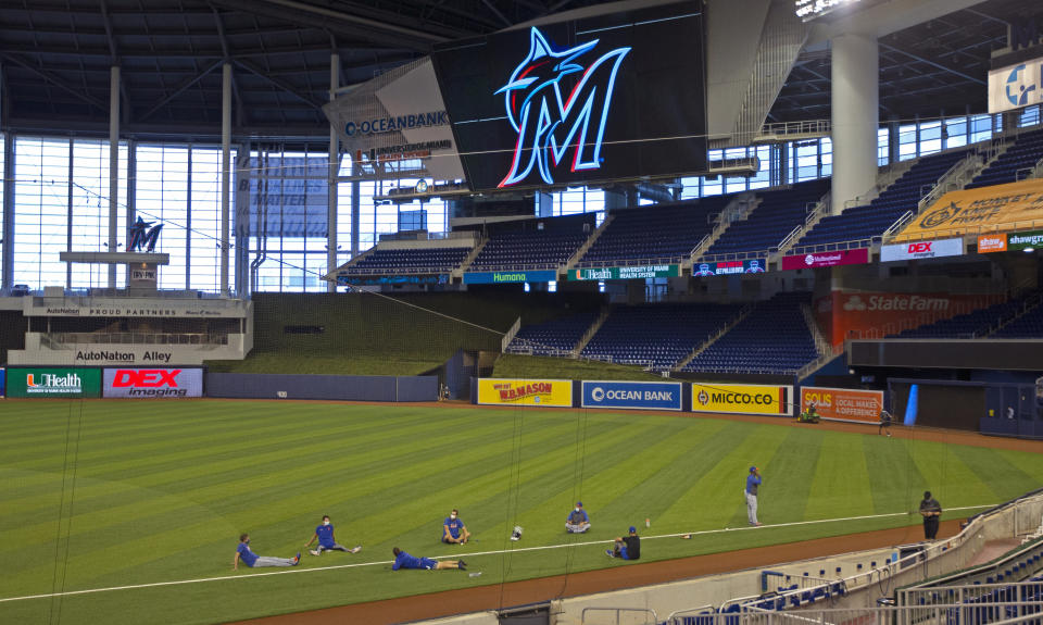 New York Mets players sit on the field before a baseball game against the Miami Marlins, Thursday, Aug. 20, 2020, in Miami. Major League Baseball says the Mets have received two positive tests for COVID-19 in their organization, prompting the postponement of two games. (David Santiago/Miami Herald via AP)