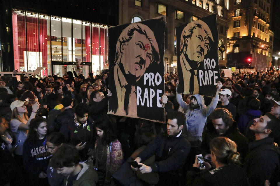 Manifestantes marchan a lo largo de la Quinta Avenida frente a la Torre Trump, el miércoles 9 de noviembre de 2016, en Nueva York, en oposición al triunfo de Donald Trump en las elecciones presidenciales. Los letreros dicen: “A favor de la violación”. (AP Foto/Julie Jacobson)