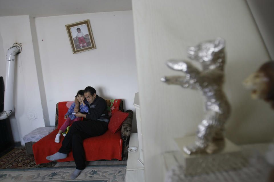 Gypsy actor Nazif Mujic hugs his daughter Sandra in the living room where his Best Actor award - the Silver Bear - decorates the shelf of his shabby home in the village of Poljice, 150 kms northeast of Sarajevo, on Wednesday, April 10, 2013. People in the Gypsy village of Poljice say they will never forget the night they almost fell off their chairs two months ago. Did they really hear the elegant woman on TV correctly? Could she really be talking about their neighbor, the toothless man who passed his days selling scrap metal and lived in the shack down the road? The camera switched to a frightened-looking Najif Mujic. Yes it was him. THEIR Nazif _ who had just left Matt Damon and Jude Law in the dust to win the best actor award at the Berlin Film Festival. (AP Photo/Amel Emric)