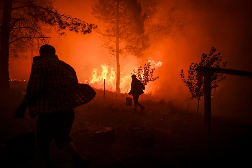 Villagers carry buckets with water to try extinguish a fire that was coming close to their houses at Amendoa in Macao, central Portugal on July 21, 2019. (Photo: Patricia De Melo Moreira/AFP/Getty Images)