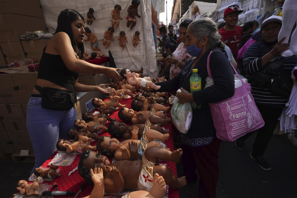 Locals handle Baby Jesus figures for sale in Mexico City, Wednesday, Jan. 25, 2023. As Mexicans prepare to celebrate "Dia de la Candelaria" or Candlemas people buy Baby Jesus figures as part of the celebration. (AP Photo/Marco Ugarte)