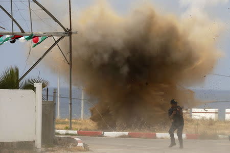 A member of Palestinian security forces loyal to Hamas demonstrates his skills as smoke rises following an explosion during a military graduation ceremony in Gaza City May 21, 2015. REUTERS/Suhaib Salem