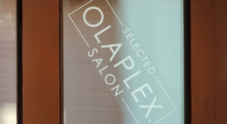 A sign for an Olaplex (OLPX) salon on a frosted glass door.