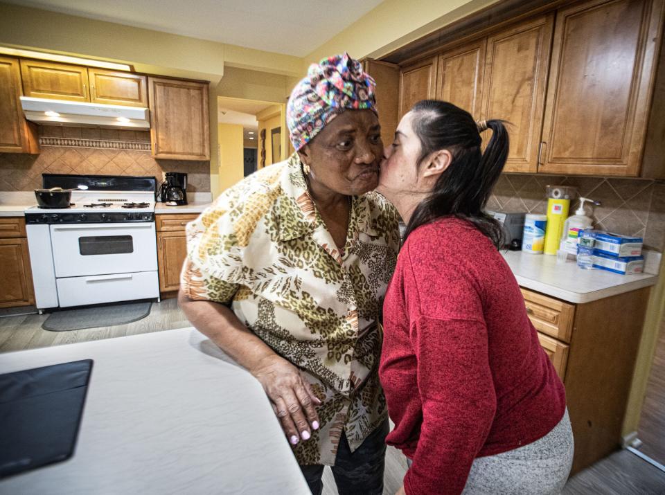 Jennifer Ojelua, a resident at Jawonio’s Johansen Home in Monsey, kisses Marie Denise Pierre, a Direct Support Professional, or DSP, Nov. 28, 2023. Jennifer is one of eight adults with severe disabilities living at the group home run by Jawonio, a non-profit that serves those with intellectual and developmental disabilities, and people with chronic medical needs. As wages for group home workers are set by the state, jobs remain empty and group homes around the state are being shuttered. Pierre and other workers say that they can’t make ends meet on the hourly wages set by the state.
