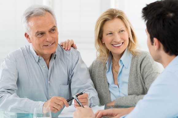 A senior couple talking to a younger man across a table