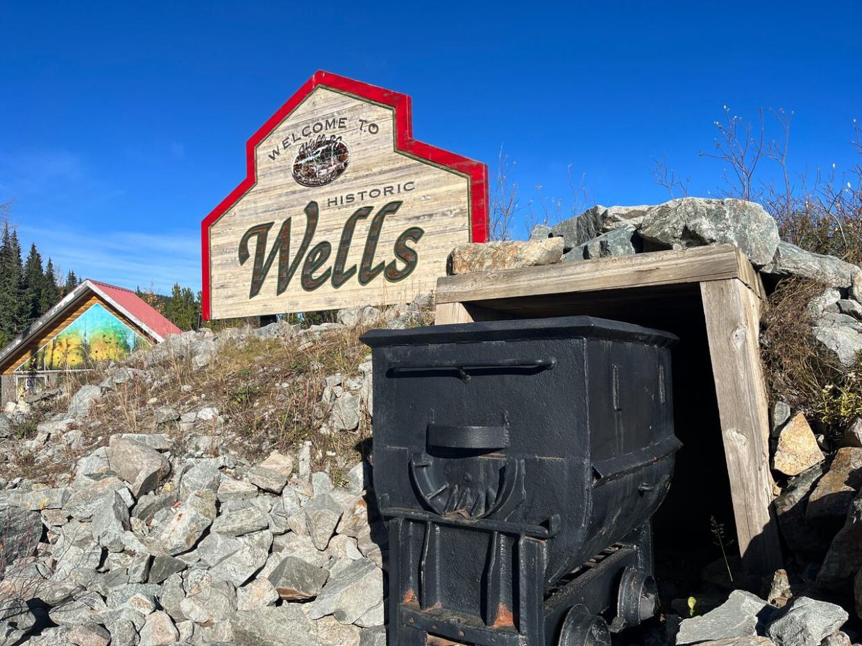 A wooden sign and mine shaft welcome visitors to the historic gold mining community of Wells, B.C. (Kate Partridge/CBC - image credit)