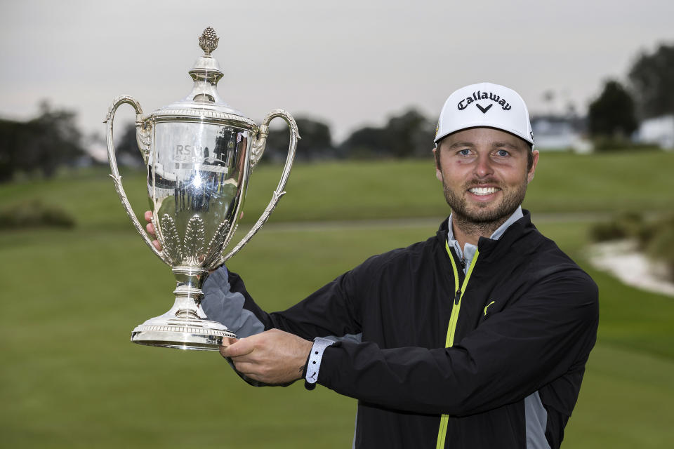 Adam Svensson, of Canada, holds the winning trophy after the final round of the RSM Classic golf tournament, Sunday, Nov. 20, 2022, in St. Simons Island, Ga. (AP Photo/Stephen B. Morton)