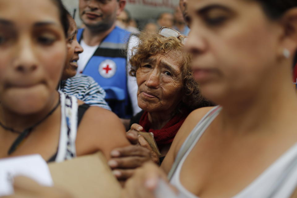 FILE - In this April 16, 2019 file photo, people wait to receive free water containers and water purification pills during the first aid shipment from the Red Cross in Caracas, Venezuela. The International Federation of Red Cross and Red Crescent Societies said on March 29th it will start distributing assistance to an estimated 650,000 people in Venezuela - an action permitted by Nicolas Maduro's government. (AP Photo/Ariana Cubillos, File)