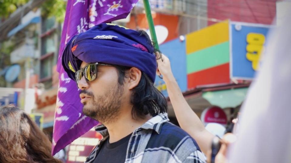 Burmese man wears sarong wrapped around his head in protest