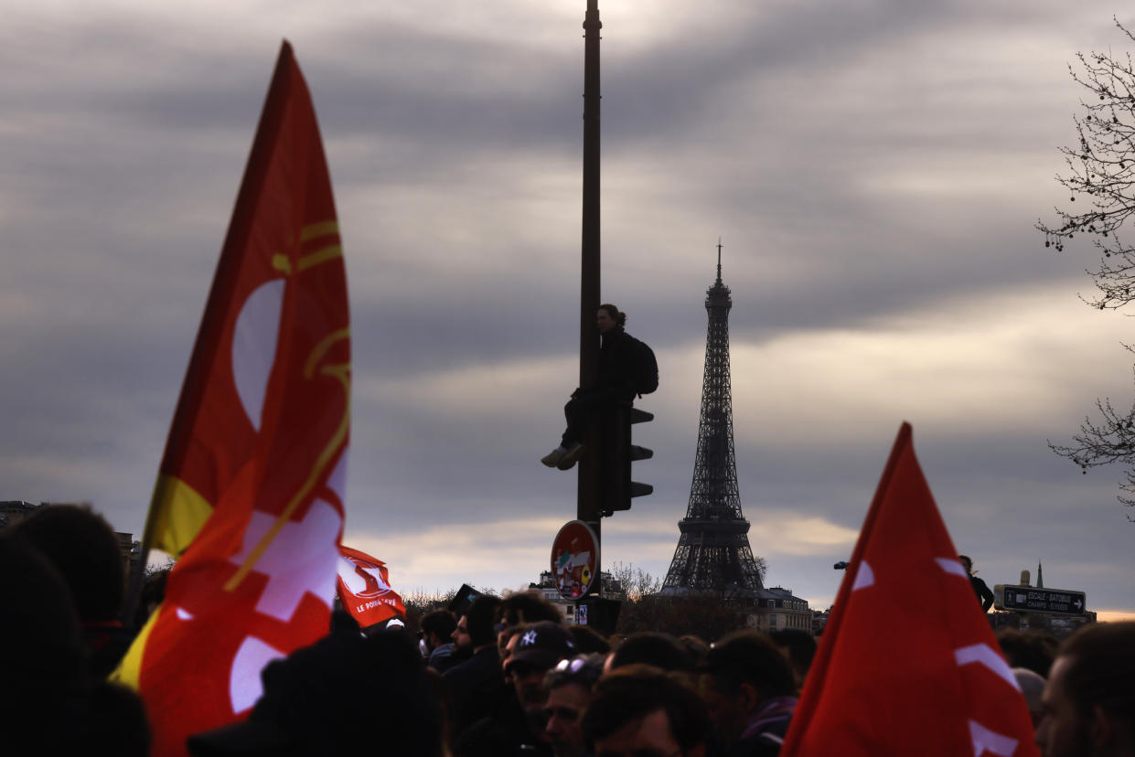 A protester sits on a street light during a gathering at Concorde square near the National Assembly in Paris, Thursday, March 16, 2023. French President Emmanuel Macron has shunned parliament and opted to push through a highly unpopular bill that would raise the retirement age from 62 to 64 by triggering a special constitutional power. (AP Photo/Thomas Padilla)