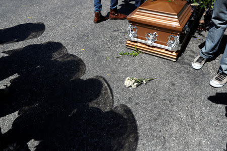 The shadows of riot policemen are cast next to the casket of a man shot dead during anti-government protests in Port-au-Prince, Haiti, February 22, 2019. REUTERS/Ivan Alvarado
