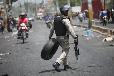 A Haitian National Police officer removes a tire from a barricade on a street in Port-au-Prince, Haiti, July 8, 2018. REUTERS/Andres Martinez Casares
